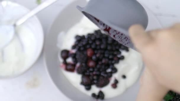 Manos femeninas añadiendo moras a un tazón de yogur — Vídeo de stock