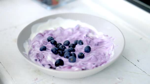 Tangan wanita mengaduk mangkuk blueberry dan yogurt dengan sendok — Stok Video