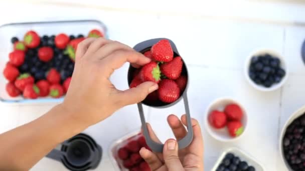 Manos femeninas sosteniendo taza medidora llena de fresas frescas — Vídeo de stock