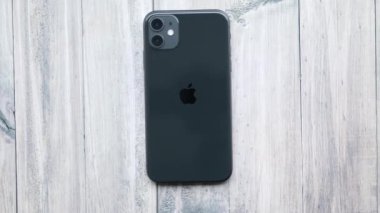Yukarıdan ahşap bir masada siyah iPhone 11