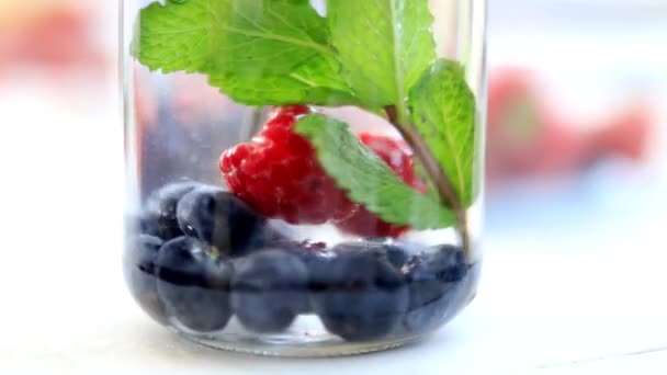 Steel straw stirring raspberries, blueberries, and mint drink — Stock Video