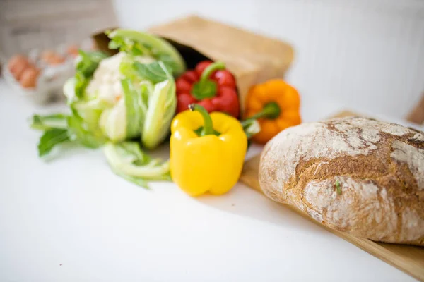 Bell peppers and cauliflower on white table next to bread