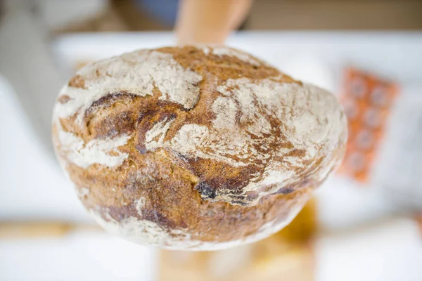 Main féminine tenant du pain au-dessus des ingrédients sur une table — Photo