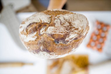 Masadaki malzemelerin üzerinde ekmeği tutan kadın eli.