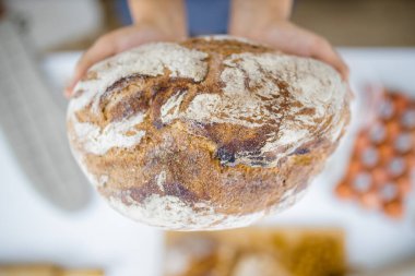 Masadaki malzemelerin üzerinde ekmeği tutan kadın elleri.