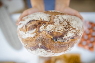 Masadaki malzemelerin üzerinde ekmeği tutan kadın elleri.