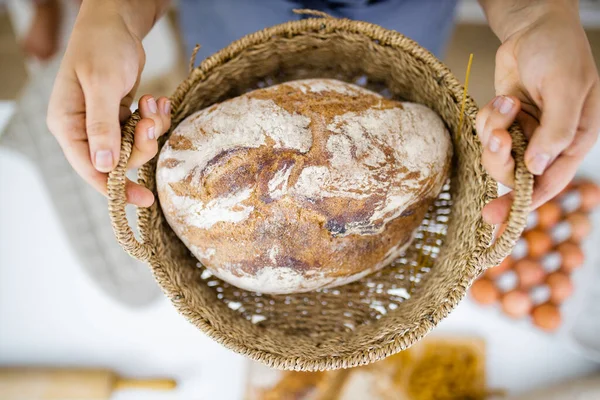 Female hands holding bread on a basket above ingredients on a table