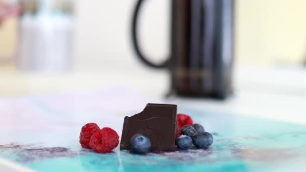 Bitten σοκολάτα μπαρ και μούρα σε ένα πολύχρωμο placemat — Αρχείο Βίντεο