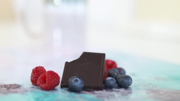 Bitten csokoládé és bogyók egy színes placemat — Stock videók