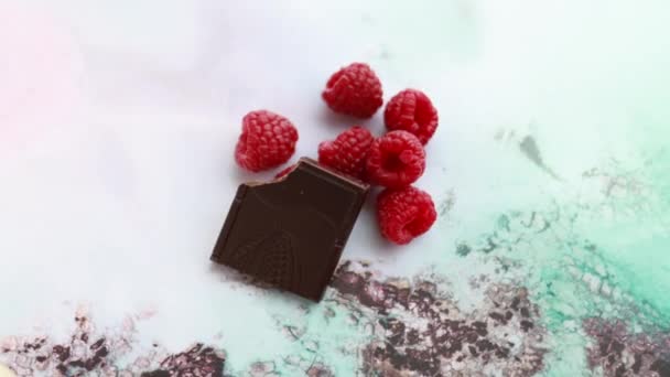 Barra de chocolate mordida y frambuesas en un mantel de colores — Vídeos de Stock