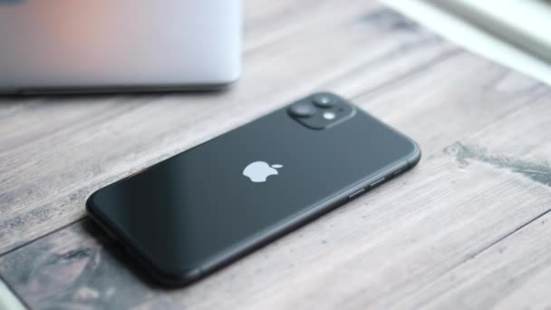 IPhone 11 en color negro que muestra en la mesa de madera — Vídeo de stock