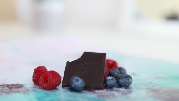 Bitten csokoládé és bogyók egy színes placemat — Stock videók