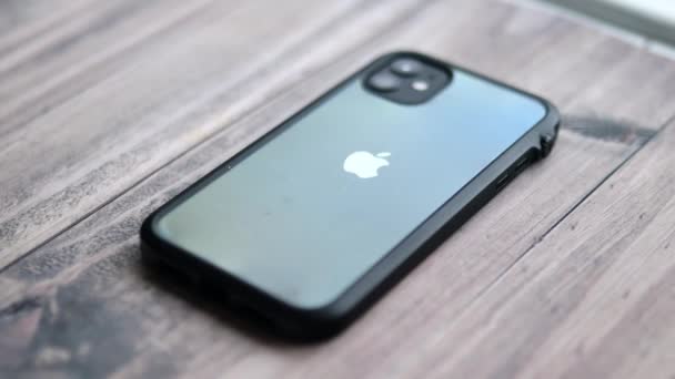 IPhone 11 con caja de borde negro que se muestra en la mesa de madera — Vídeo de stock