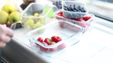 Kadın eli, konteynıra yaban mersini ve çilek koyar.