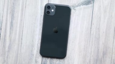 Yukarıdan ahşap bir masada siyah iPhone 11