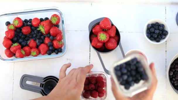 Tangan wanita memegang blueberry dan raspberry dalam wadah plastik — Stok Video