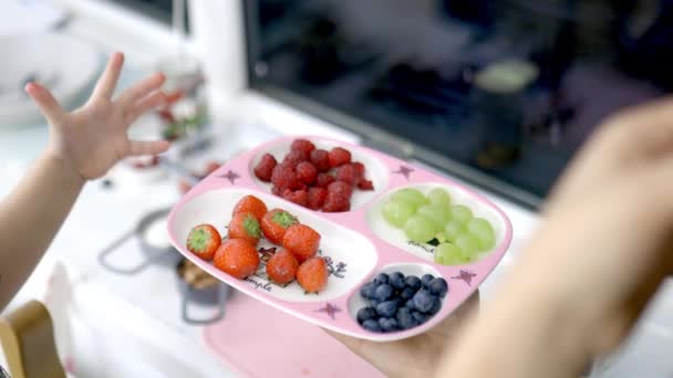 Mains féminines cueillant des fraises dans un plateau rose avec des baies — Video