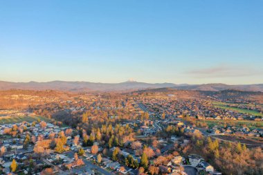 Arka planda dağları olan ağaçlarla çevrili huzurlu bir kasaba.