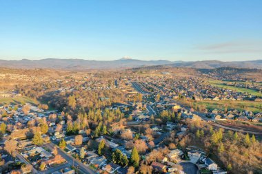 Arka planda dağları olan ağaçlarla çevrili huzurlu bir kasaba.