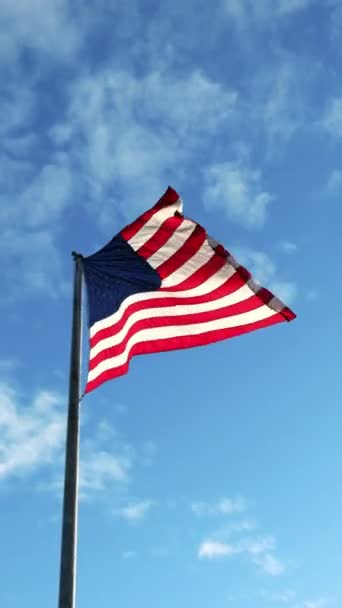 Tiro vertical da bandeira americana acenando no vento e céu azul como fundo — Vídeo de Stock
