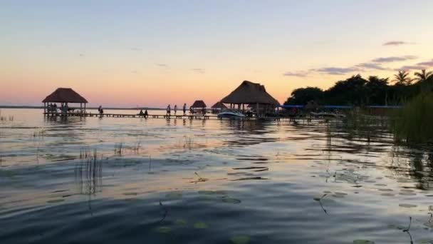 4k Vista de Bungalows em uma doca em Lago Bacalar com um pôr do sol colorido impressionante — Vídeo de Stock