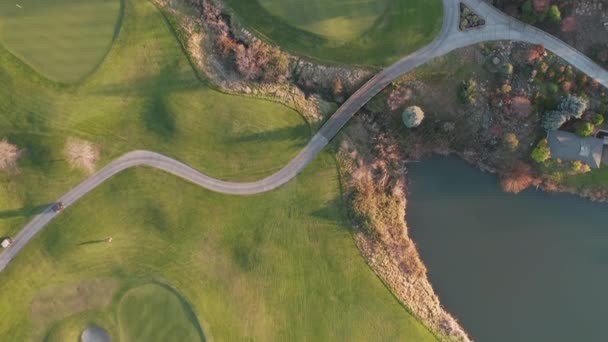 4k tir aérien sur un terrain de golf avec herbe verte et les gens se déplaçant autour — Video