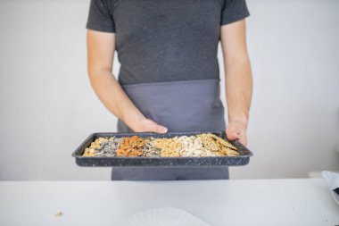 Erkek el siyah bir tepsi fındık ve tohum tutuyor.