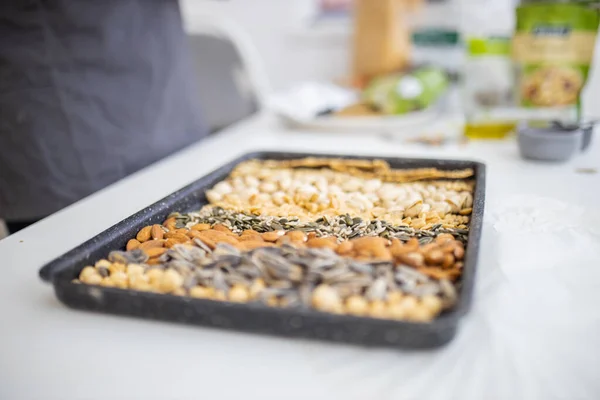 Zwarte schaal van noten en zaden boven een witte tafel — Stockfoto
