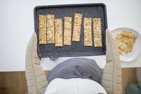 Handschuh in der Hand hält ein schwarzes Tablett mit schwedischem Knäckebrot — Stockfoto