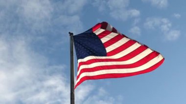 Arka planda mavi gökyüzü olan rüzgarla dalgalanan Amerikan bayrağı