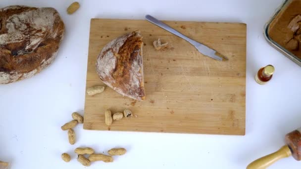 Pół bochenka chleba i orzeszki ziemne na desce do krojenia — Wideo stockowe