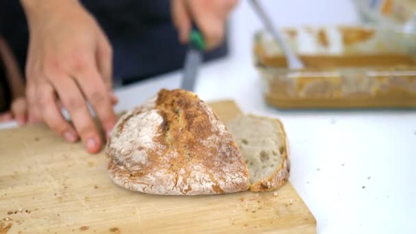 Vrouwelijke handen snijden brood op een snijplank — Stockvideo