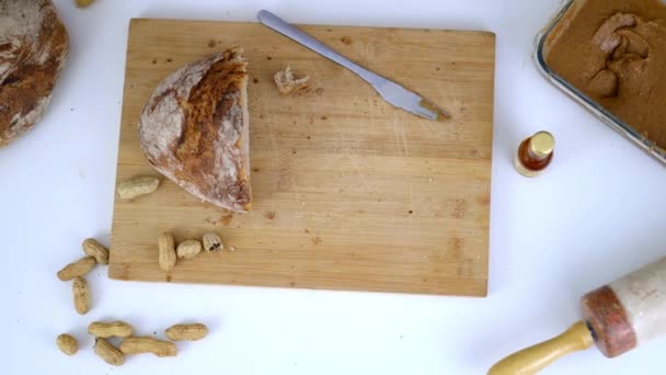 Een half brood en pinda 's op een snijplank — Stockvideo