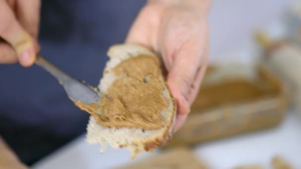 Dłonie kobiet rozkładające masło orzechowe na plasterku chleba — Wideo stockowe