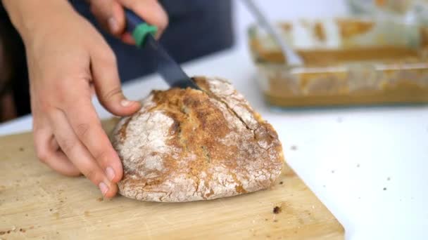 Kvinnliga händer skär bröd på en skärbräda — Stockvideo