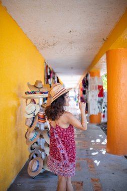 Güzel esmer kadın kırmızı elbise ve hasır şapka giyiyor.