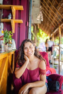 Güzel bir kadın bir kafe dışındaki koltukta oturuyor.