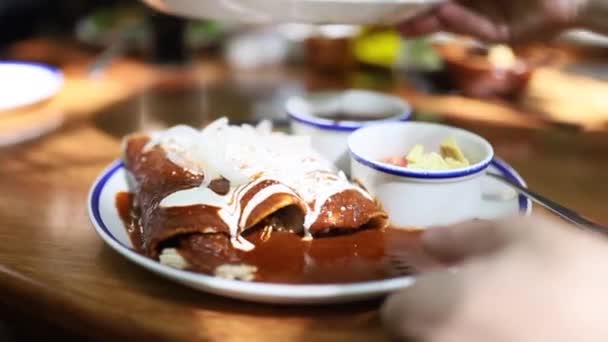 Tiro que move-se rapidamente da placa de Enchiladas às batatas doces fritas sobre uma mesa — Vídeo de Stock