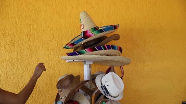 Video van een vrouw plukken een Sombrero uit stapels van traditionele Mexicaanse hoeden — Stockvideo