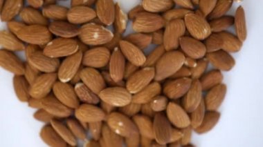 Beyaz bir masada kalp şeklinde küçük bir badem yığını.