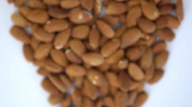 Beyaz bir masada kalp şeklinde küçük bir badem yığını.