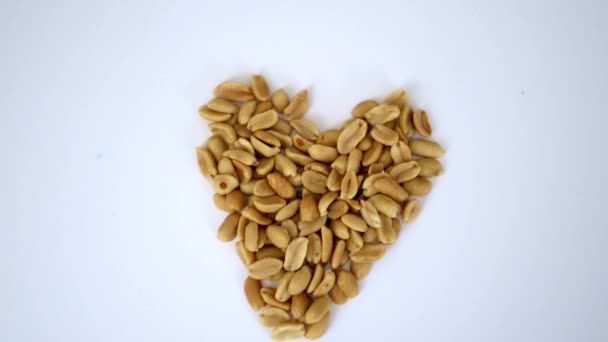 Liten hög med jordnötter i hjärtform på ett vitt bord — Stockvideo