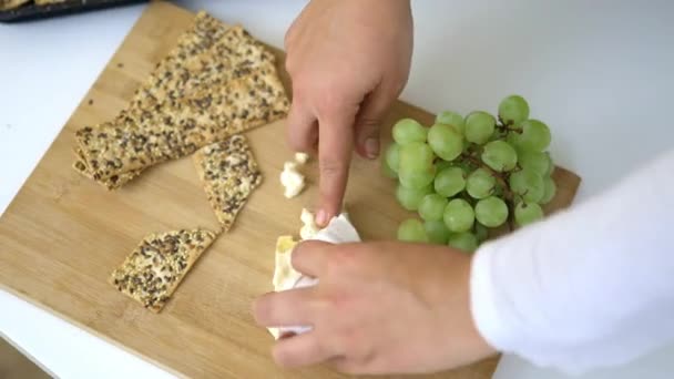 Vrouwelijke handen plukken kaas en Zweedse knäckebröd van snijplank — Stockvideo