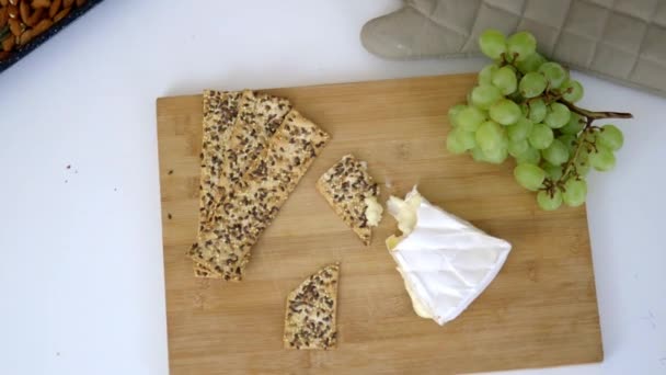 Zweeds knäckebröd, druiven en een stuk kaas op een snijplank — Stockvideo