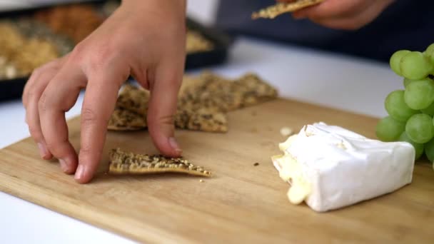 Vrouwelijke handen plukken kaas en Zweedse knäckebröd van snijplank — Stockvideo