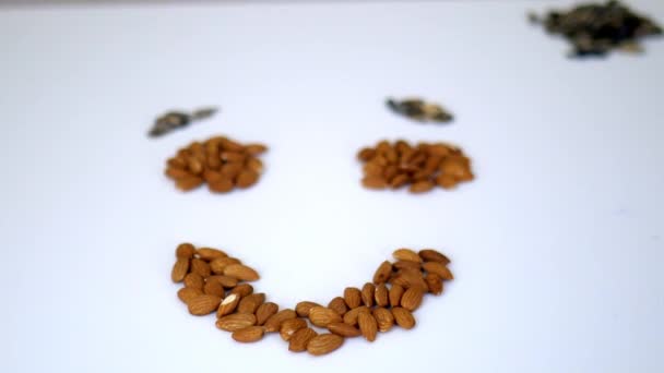 Pequeñas pilas de almendras y semillas de girasol en forma de cara sonriente — Vídeos de Stock