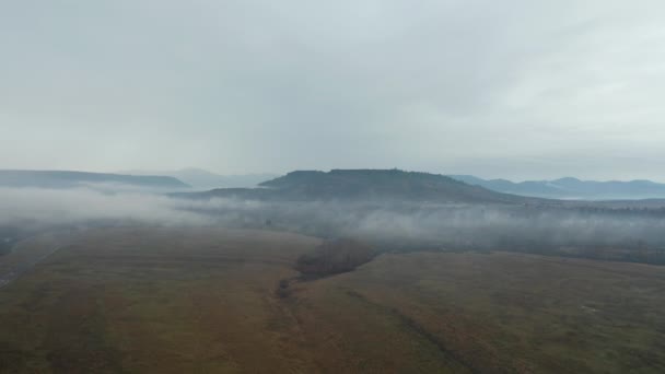 4k vista aérea voando sobre nevoeiro para a tabela de rochas e montanhas no fundo — Vídeo de Stock