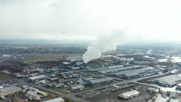 4k bovenaanzicht vliegen in de richting van een industriële rook stapel terwijl auto 's rijden door — Stockvideo