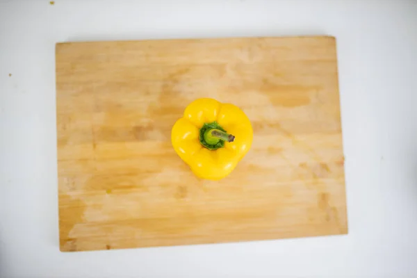Желтый перец на разделочной доске над белым столом — стоковое фото