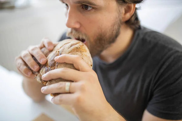 驚いたことに、白いテーブルでパンを食べて男を見て — ストック写真